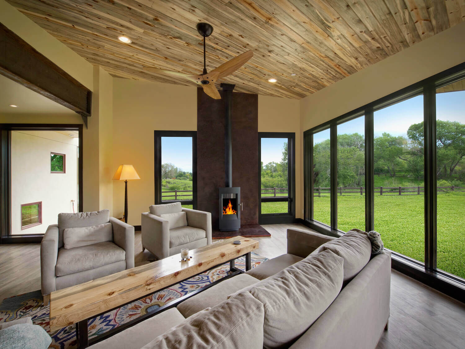 custom home living room with large windows and wood-burning fireplace
