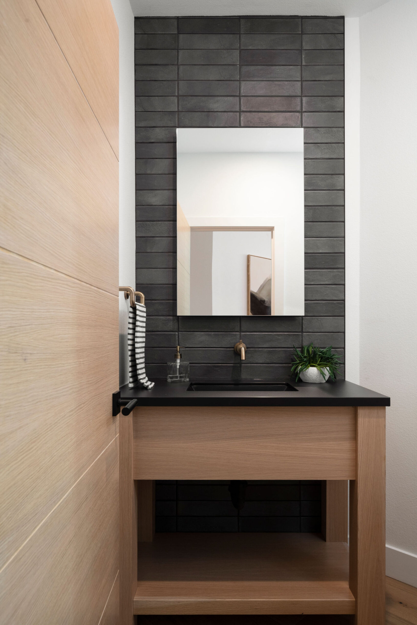 Wildflower custom home - wood powder bath vanity with matte black subway tile