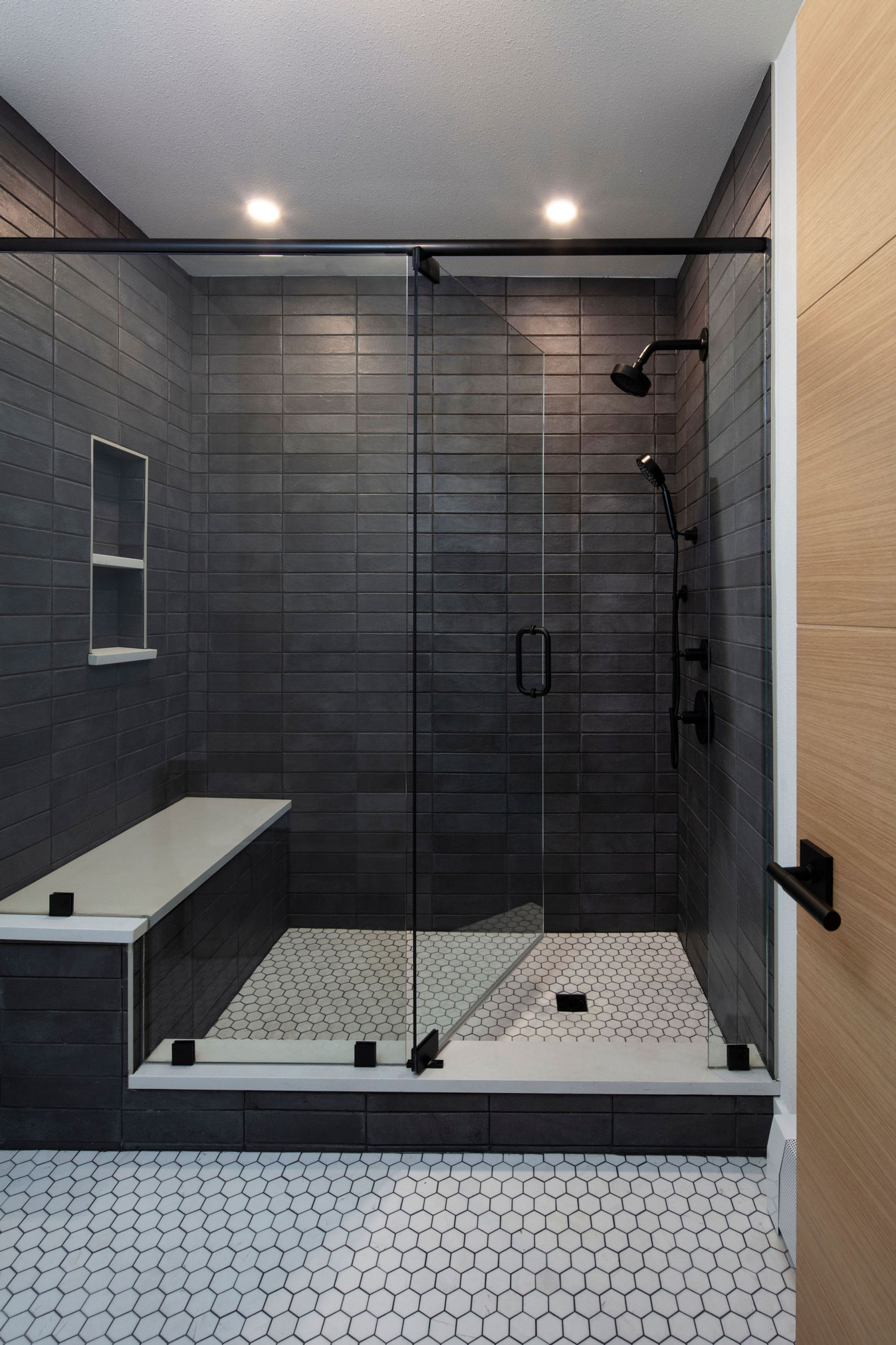 Wildflower custom home - walk-in glass shower with hexagonal floor tile and matte subway tile on the walls